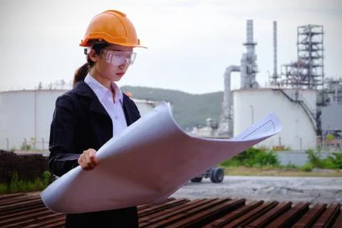 The engineer is checking a layout with large industry background. Stock Photos
