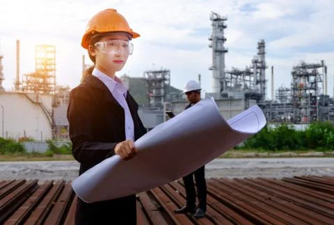 The engineer is checking a layout with large industry background. Stock Photos