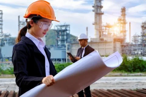The engineer is checking a layout with large industry background. Stock Photos