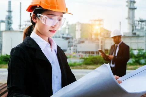 The engineer is checking a layout with large industry background. Stock Photos