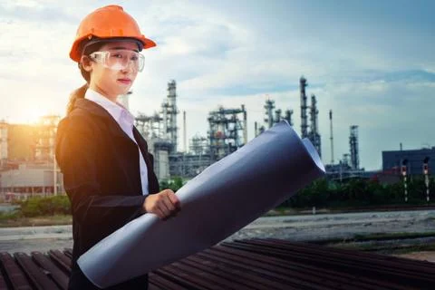 The engineer is checking a layout with large industry background. Stock Photos
