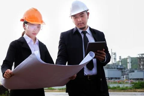 The engineer is checking a layout with large industry background. Stock Photos