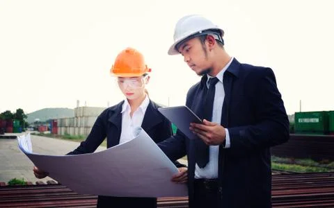 The engineer is checking a layout with large industry background. Stock Photos