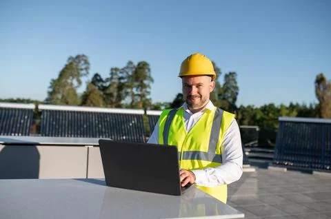 Engineer checking renewable energy installation using laptop on rooftop 写真素材