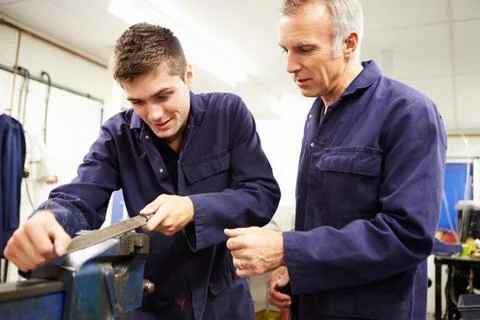 Engineer checking trainee's work on factory floor Stock Photos