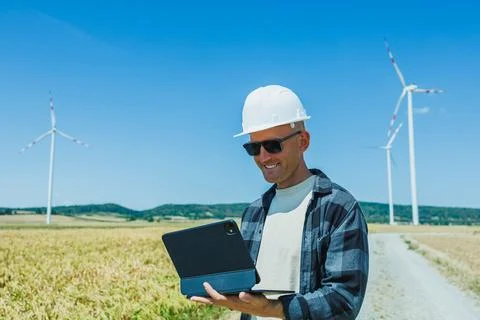 Engineer checks data in a field with wind turbines during sunny day Foto stock