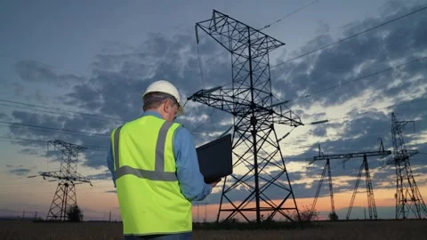 Engineer checks equipment with laptop walking to power transmission lines Stock Footage 268749779