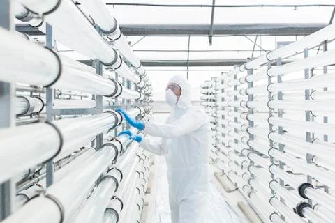 Engineer in clean suit examining pipes in laboratory Stock Photos