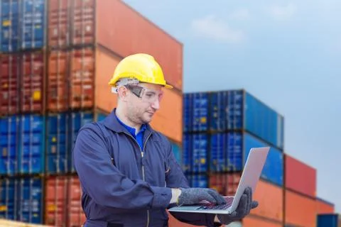 Engineer with clipping path in hardhat holding laptop at containers cargo Фото