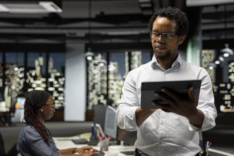 Engineer coding with tablet in startup office, refining machine learning models Foto stock