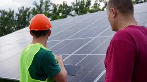 An engineer communicates with a customer against the background of solar panels. Stock Footage 321967376
