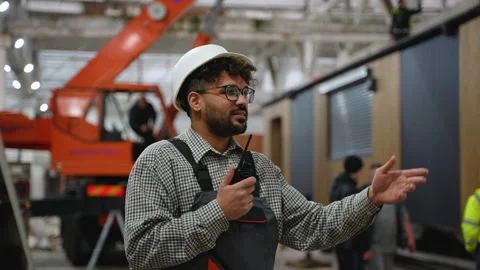 Engineer communicating with walkie talkie in warehouse Stock Footage 313084778