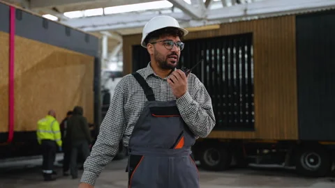 Engineer communicating with walkie talkie in warehouse Stock Footage 313085408