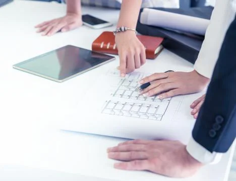 Engineer conctractor teamwork checking out a housing project paper plan Stock Photos