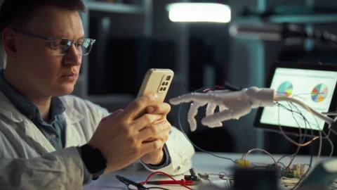 Engineer conducts research on smartphone technology while analyzing robotic Stock Footage 331296722