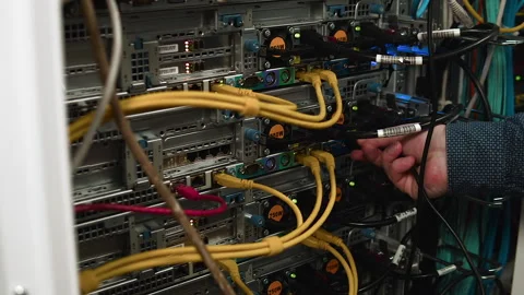 The engineer connects the cable to the system unit of a large server cabinet. Stock Footage 165267787