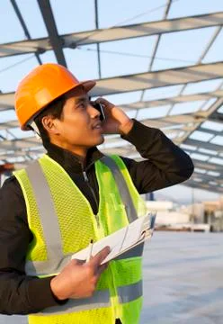 Engineer construction talking mobile phone under new building Foto stock