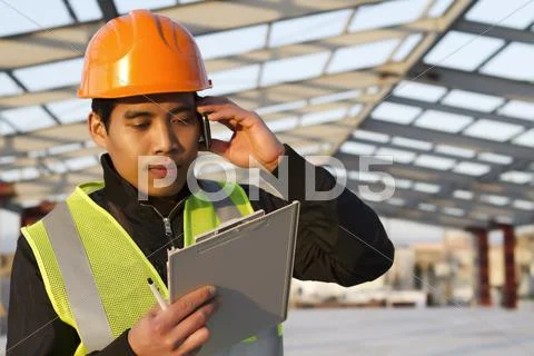 Engineer construction talking mobile phone under new building Stock Photos