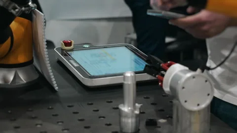 Engineer controlling industrial robot using touchscreen interface. 動画素材 347782846