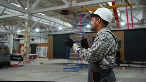 Engineer coordinating lifting operations in spacious industrial facility Stock Footage 313090604
