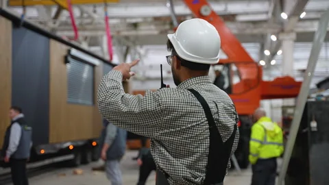 Engineer coordinating prefabricated house transportation in factory Stock Footage 313084150
