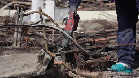 Engineer cutting length of metal at a building destroyed by wildfire Stock Footage 300966329