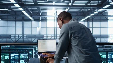 Engineer in data center coding on laptop, optimizing resource utilization Stock-Fotos