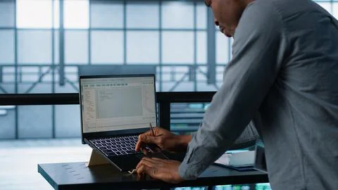 Engineer in data center coding on laptop, optimizing resource utilization Stock Photos
