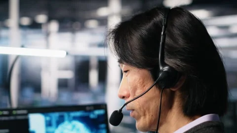 Engineer in data center wearing headset assisting users with AI Stock Footage 313635326