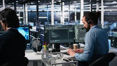 Engineer in data center wearing headset assisting users with AI Stock Footage 313638241