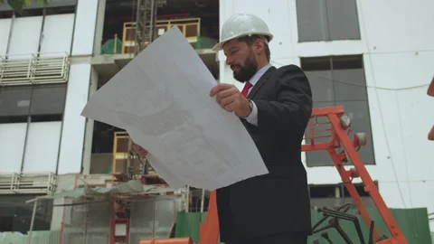 An engineer, developer at a construction site checks on the drawings at what Video stock 167731119