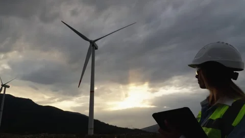 An engineer with a digital tablet studies data from wind turbines, analyzing the Stock Footage 270990129