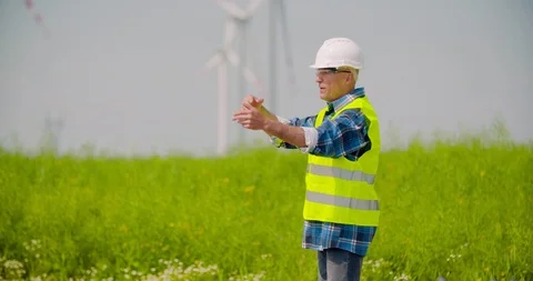 Engineer directing by windmills in farm against sky Stock Footage 106493612