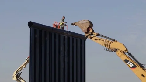 Engineer directs excavator from forklift on large wall Stock Footage 111849056