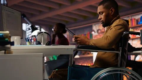 Engineer with disability coding AI algorithms in inclusive startup using tablet Stock Photos