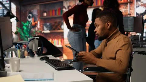 Engineer with disability coding AI algorithms in inclusive startup using tablet Foto stock