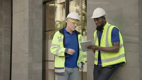 Engineer discusses work with an African American engineer outside the building. Stock Footage 144278199