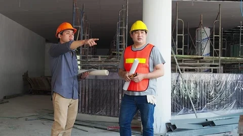 Engineer discussing with foreman about project in building construction site Stock Footage 195930825