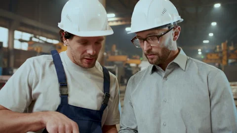 Engineer Discussing Technical Drawings with Worker in Industrial Plant Stock Footage 296262231