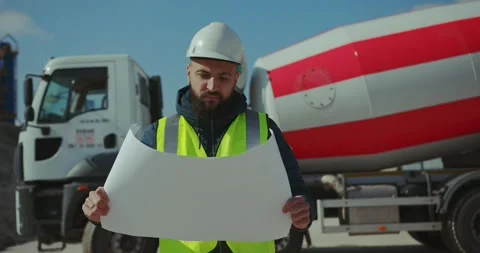 An engineer with a drawing in his hands on the background of a concrete mixer. Stock Footage 277595735