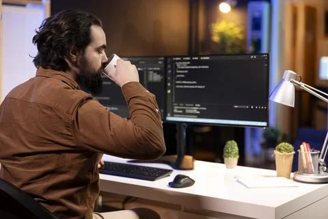 Engineer drinking coffee in the morning at PC, increasing data security Foto stock