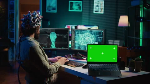 Engineer with EEG headset on merging with AI, green screen laptop Stock Footage 267045525