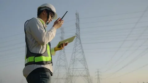 Engineer Electric talking on walkie talkie near high voltage tower. Stock Footage 148353967
