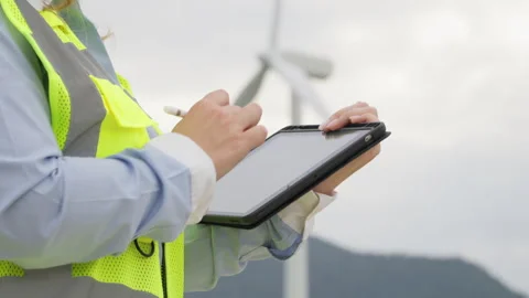 Engineer with electronic tablet near windmill: technical consideration for Stock Footage 252130579