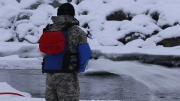 Engineer emptying hose in ice covered river Stock Footage 85719143