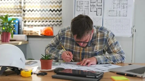 Engineer examines details, engineer carefully inspects technical sketches at Stock Footage 319960840