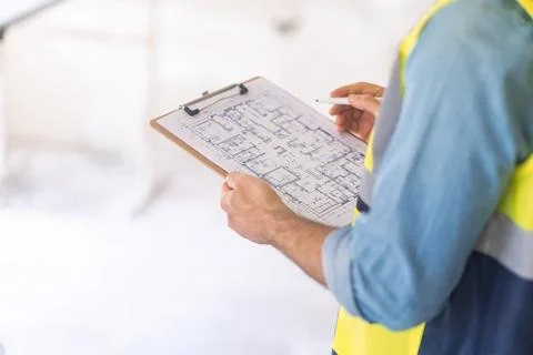 Engineer examining construction documentation holding clipboard and pen in hands Stock Photos