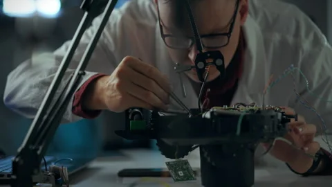 Engineer examining electronic components while repairing a robotic device in Stock Footage 289571094