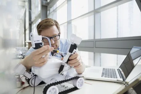 Engineer examining robot at desk Stock Photos