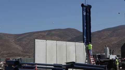 Engineer fastens steel structure to a large wall Stock Footage 114084988